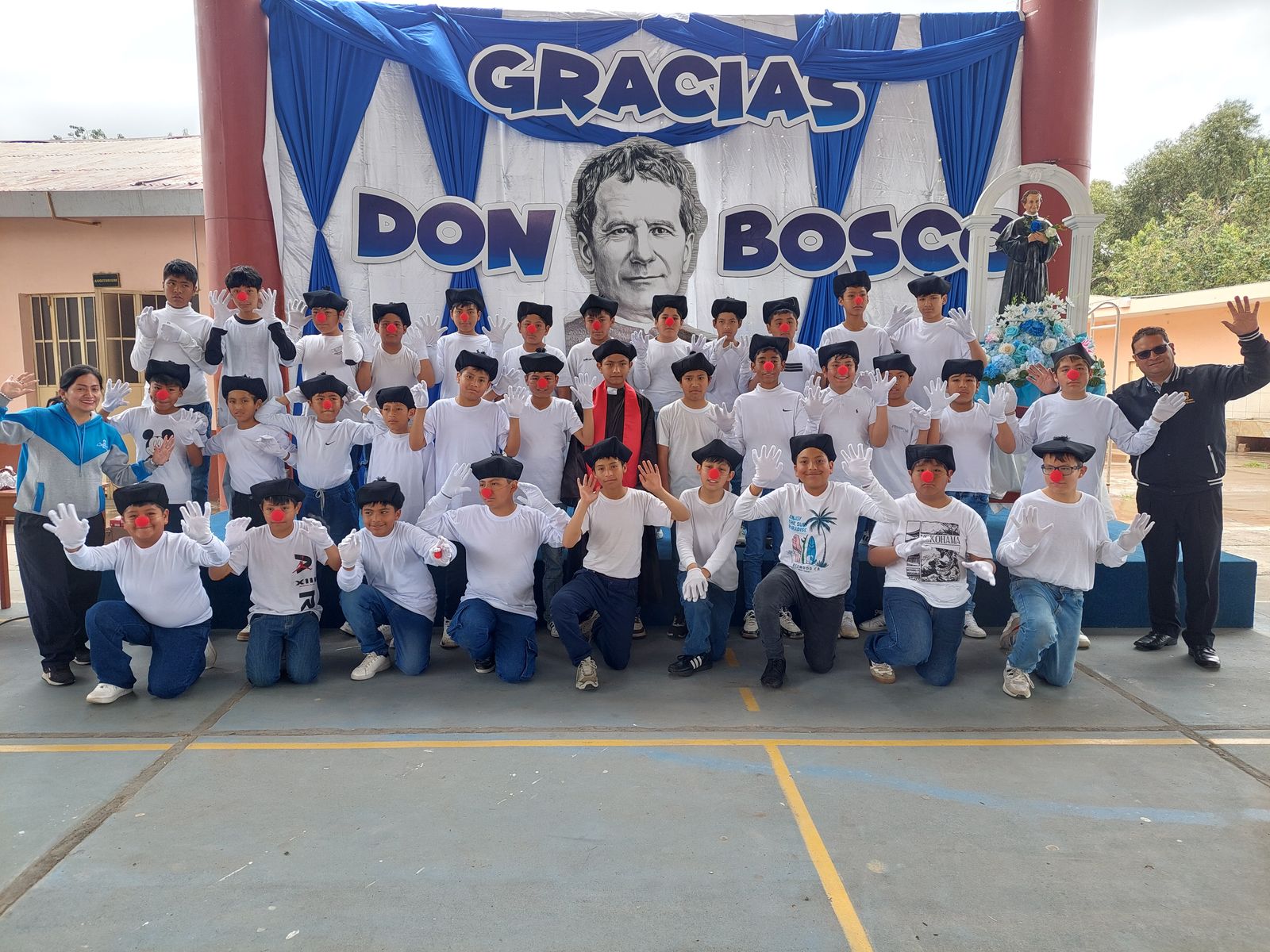 Estudiantes con gorros y guantes blancos agradeciendo a Don Bosco