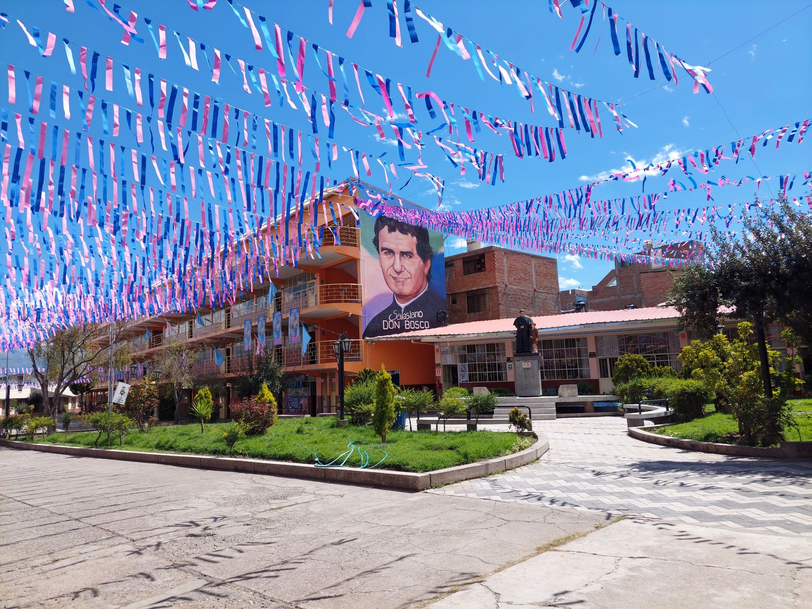 El patio del colegio con el mural de Don Bosco, adornado para la fiesta
